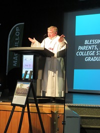 Priest on stage at lectern praying