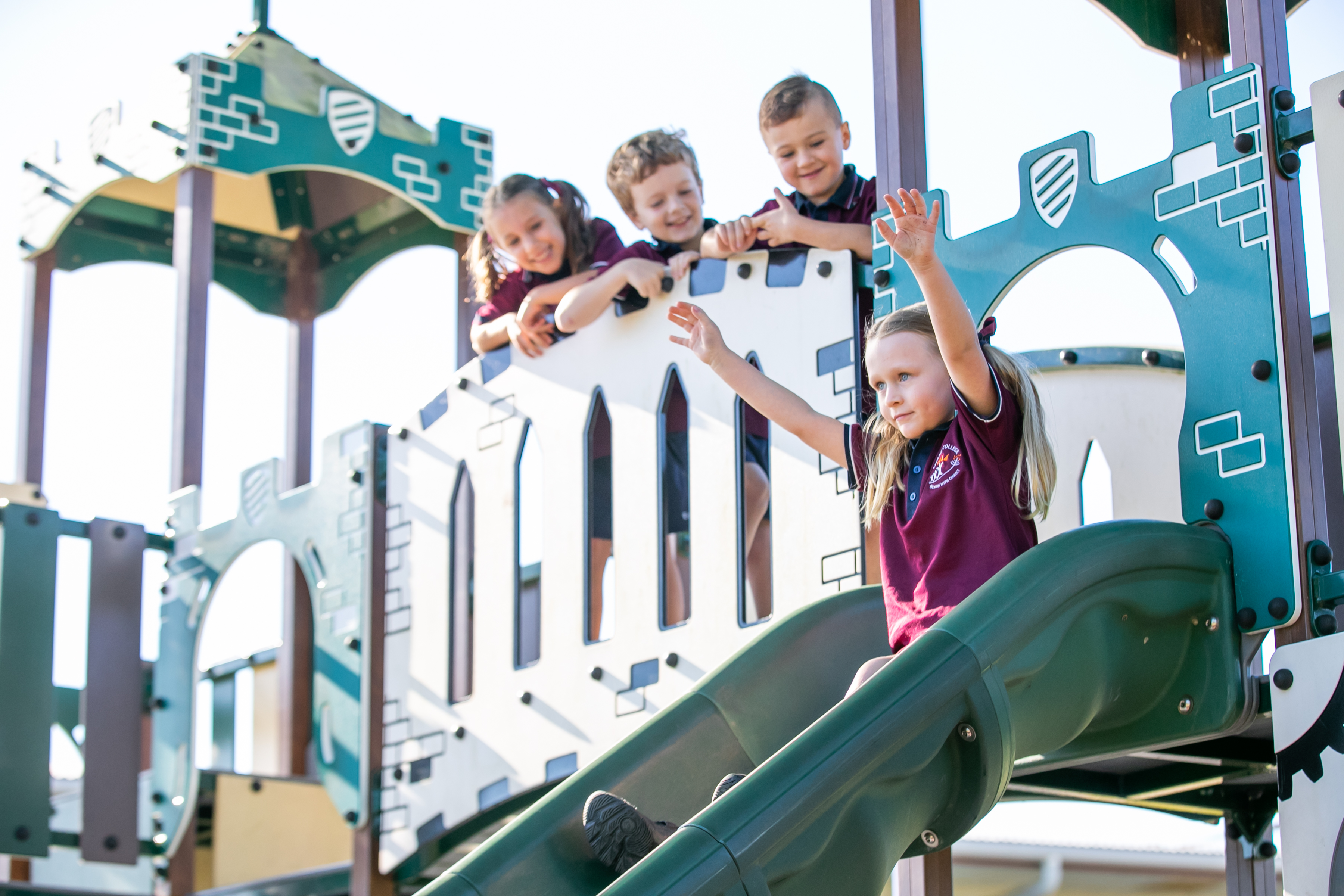 Students playing on a school playground with climbing equipment and slide during outdoor break time