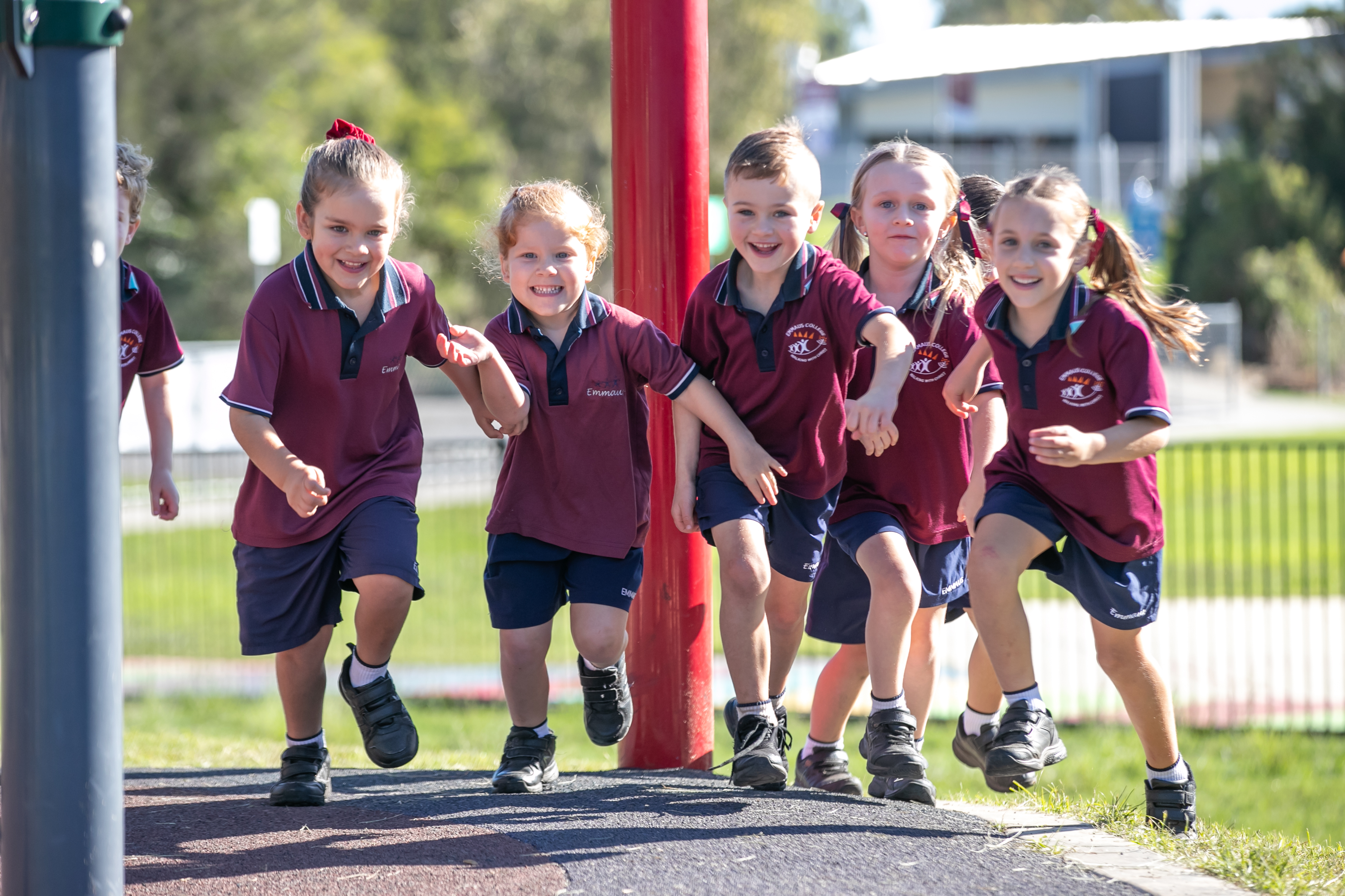 Primary students in uniform running together on a school playground during outdoor play time