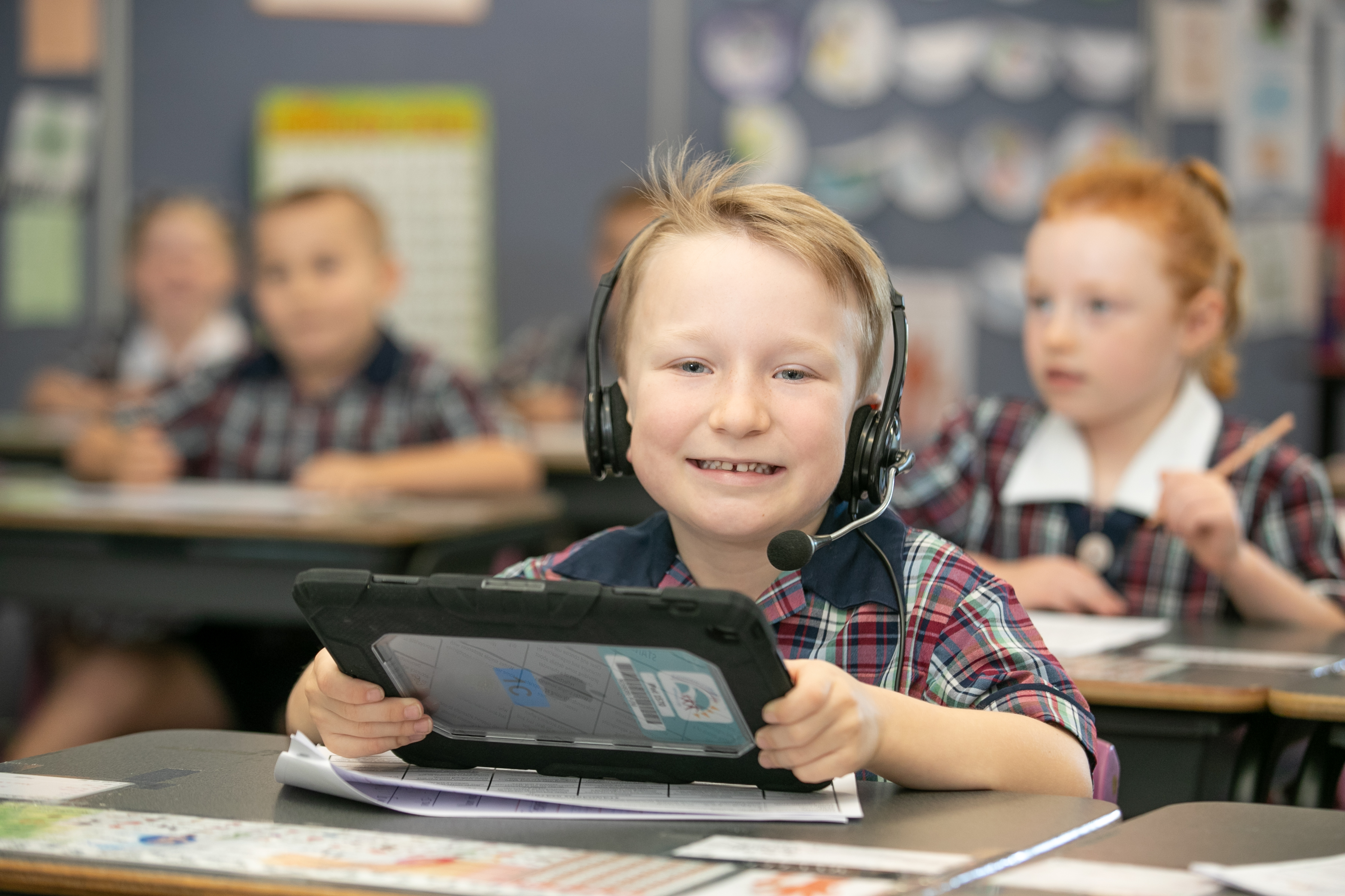Young student using a tablet with headphones during a classroom learning activity