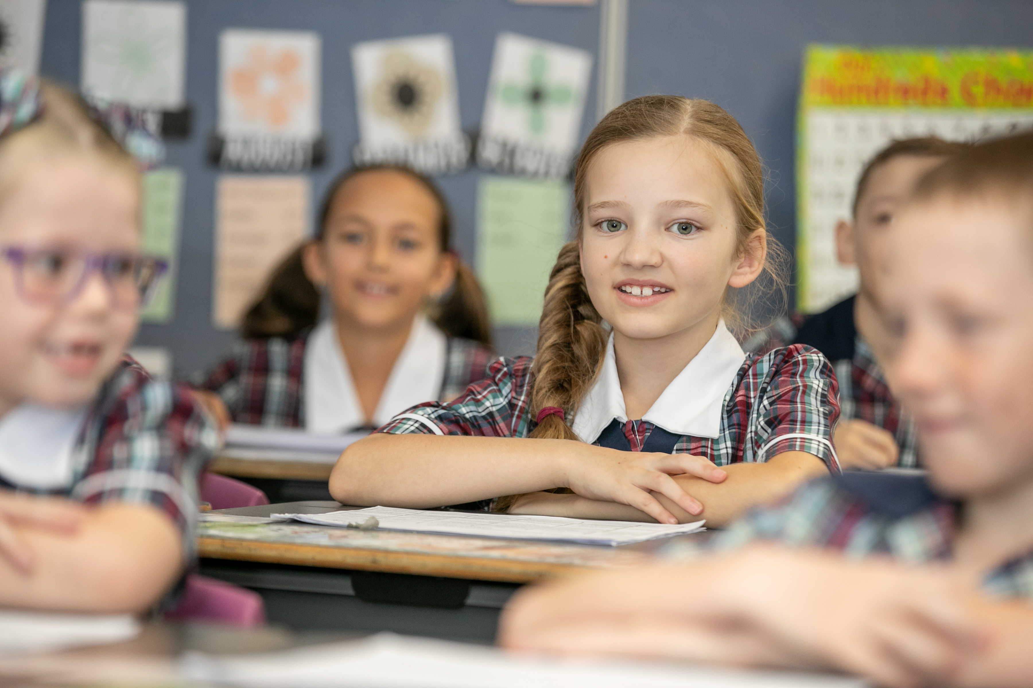 Students seated in a classroom engaged in learning with books and classwork on desks