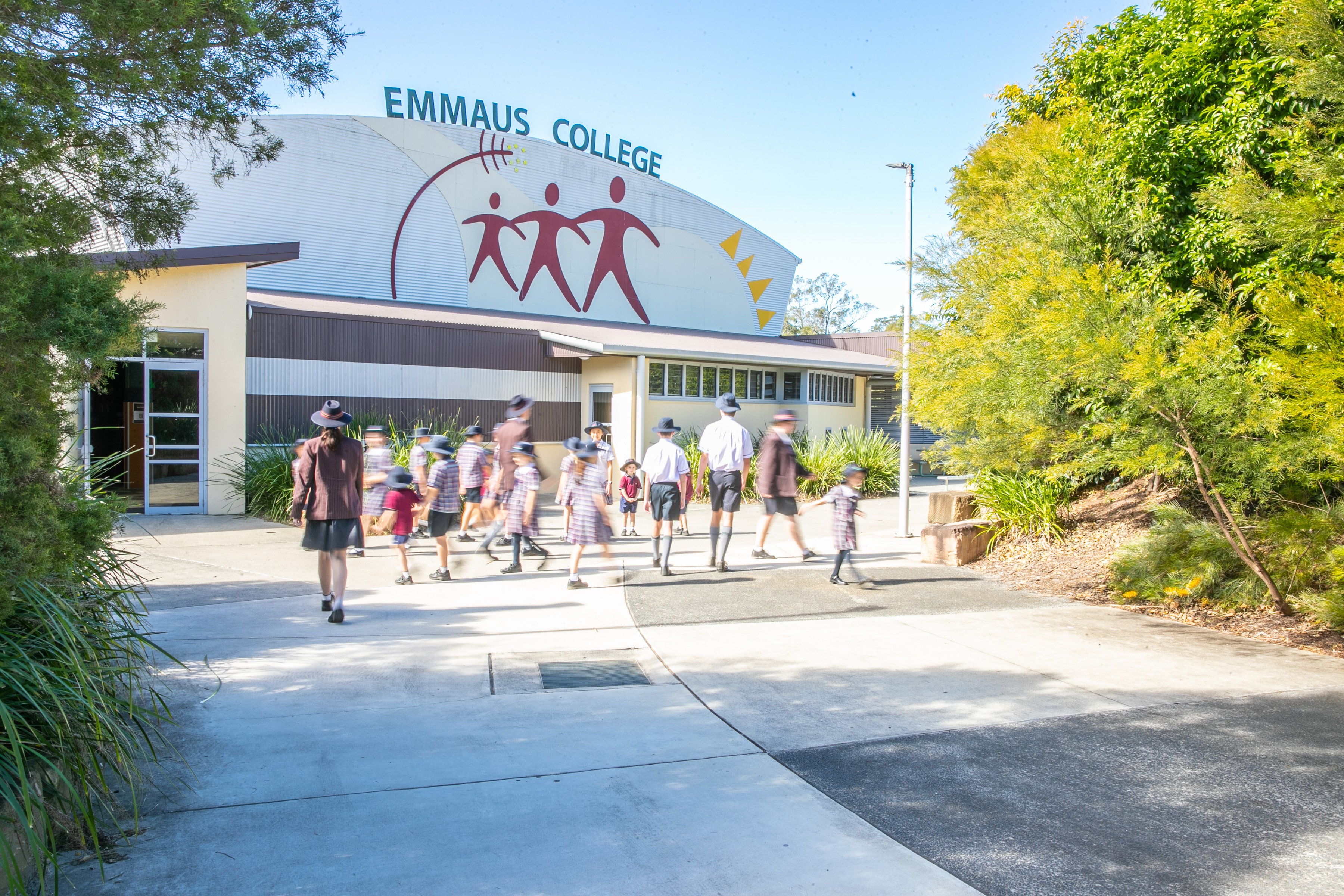 Students walking through Emmaus College grounds towards school buildings in a welcoming campus environment