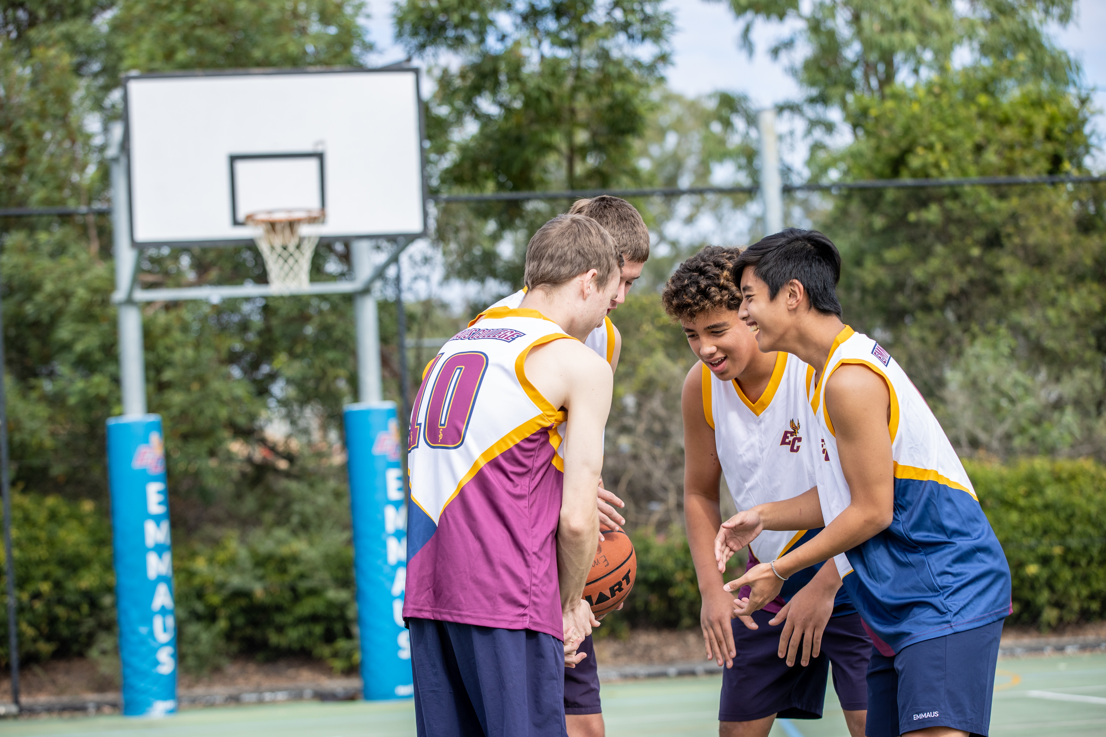 Students playing basketball on an outdoor court, collaborating as a team during a game