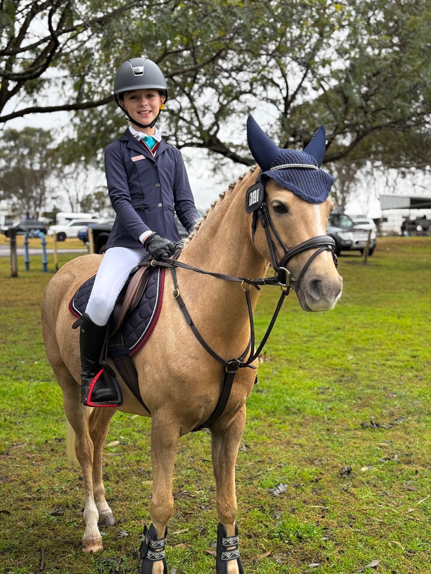 Student rider in competition uniform seated on a horse during an equestrian event