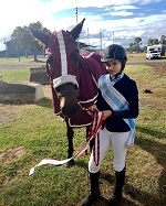 Student with horse wearing ribbons after equestrian event achievement
