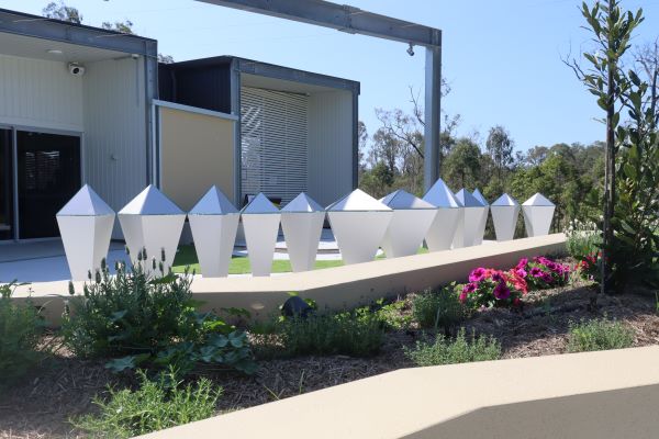 Outdoor prayer garden space with landscaped plants and decorative white sculptures near school buildings