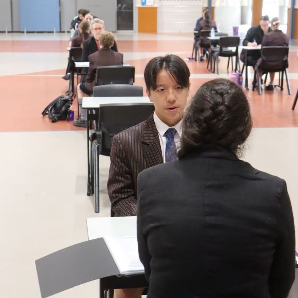 Close up of an Emmaus College student being interviews by a lady with a braid and a black suit